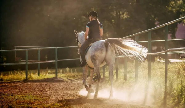 Mujer montando un caballo en el polvo en el paddock — Foto de Stock