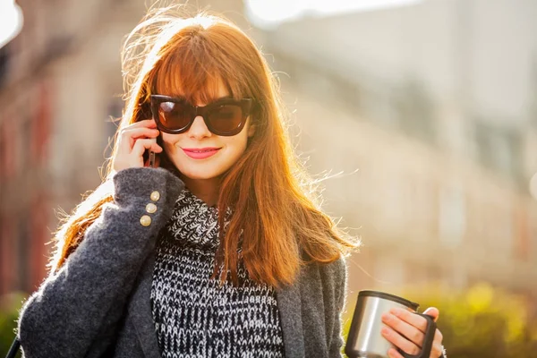 Vrouw met koffiekopje praten op mobiele telefoon in de stad — Stockfoto