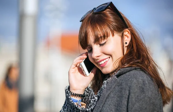 Vrouw zittend op het bankje bij de straat van de stad en het gebruik van de telefoon — Stockfoto