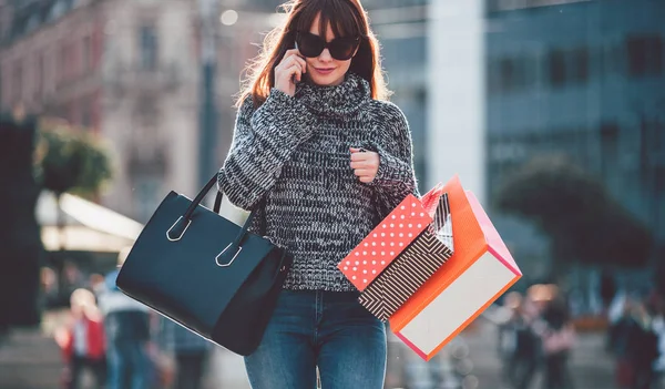 Женщина в городе гуляет с сумками и разговаривает по телефону — стоковое фото