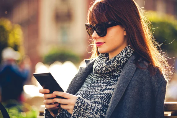 Mujer bonita usando tableta o lector de libros electrónicos sentado en la ciudad, escena urbana —  Fotos de Stock