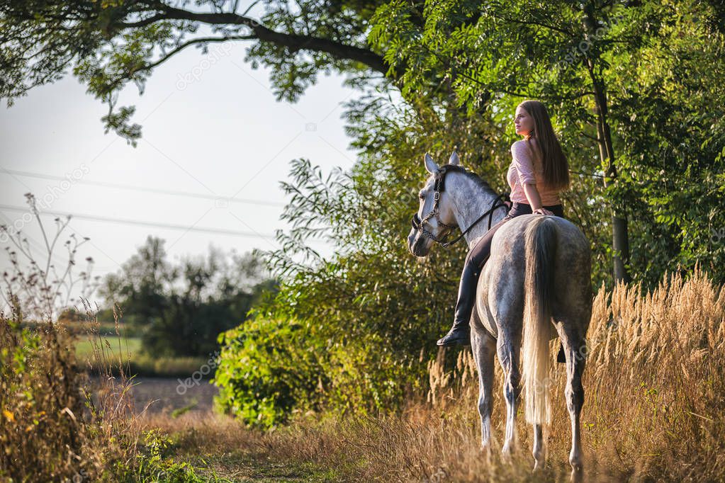 Woman riding a horse during sunset in countryside
