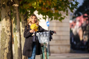 Kız sokakta vintage Bisiklet tutan renkli sonbahar yaprakları ile