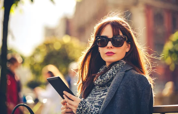 Mooie vrouw met behulp van tablet of ebook reader zitten in de stad, stedelijke scène — Stockfoto