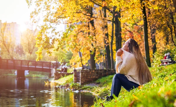 Mulher relaxada por lago no colorido parque de outono — Fotografia de Stock