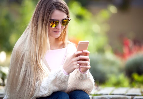 Молода жінка використовує мобільний телефон в саду — стокове фото