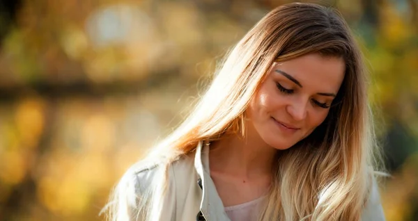 Menina sorridente no casaco no fundo do outono no dia ensolarado — Fotografia de Stock