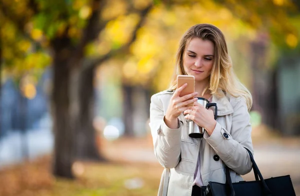 Hermosa mujer usando teléfono inteligente caminando calle otoño colorido —  Fotos de Stock