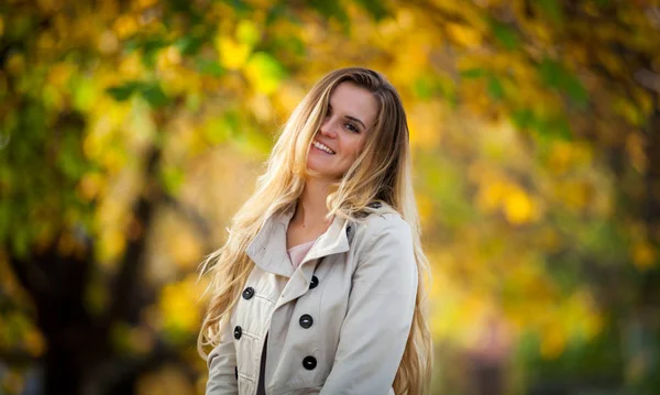 Fröhliche Frau, die in der Stadt unter bunten Herbstbäumen spaziert 2 — Stockfoto