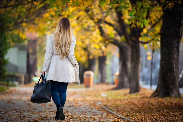 Γυναίκα στο παλτό περπατώντας στην όμορφη φθινοπωρινή street, πίσω θέα στην πόλη — Φωτογραφία Αρχείου