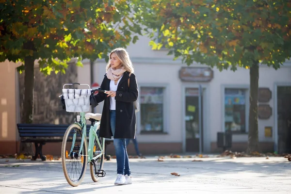 Женщина с велосипедом в городских пейзажах осенью — стоковое фото