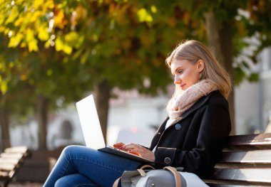 Kentin renkli sonbahar ağaçların altında sokak dizüstü bilgisayar kullanan kadın
