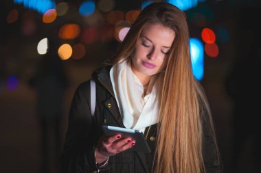 Güzel kadın tablet şehirde gece kullanma.