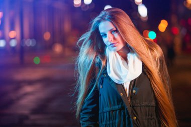 Gece şehirde, kırmızı ve mavi neon ışıkları arasında kadın