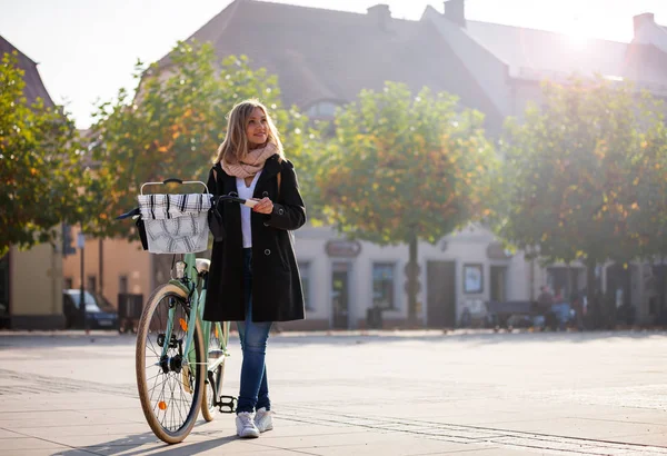 Женщина с велосипедом в городских пейзажах осенью — стоковое фото