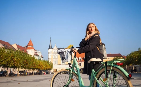 Woman with bike in urban scenery during autumn — Stock Photo, Image