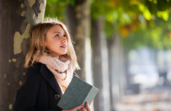Mujer fascinada leyendo un libro al aire libre bajo coloridos árboles otoñales —  Fotos de Stock
