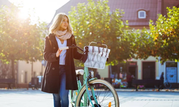 Девушка в пальто с ретро-велосипедом на осенней улице — стоковое фото