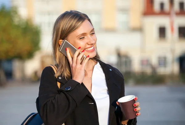 Meisje met koffiekopje praten over de telefoon en wandelen op de straat — Stockfoto