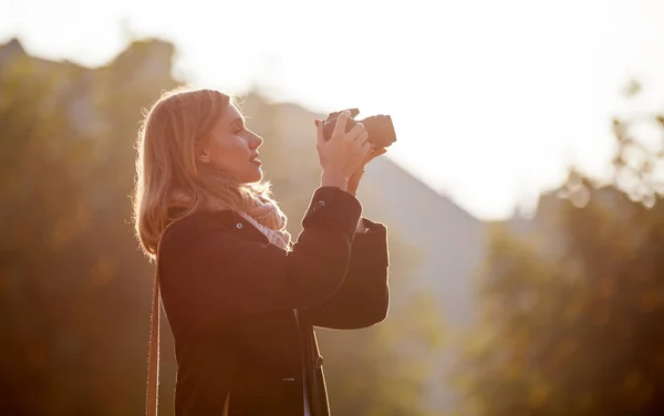 Girl taking picture with camera during sunset in the city — Stock Photo, Image