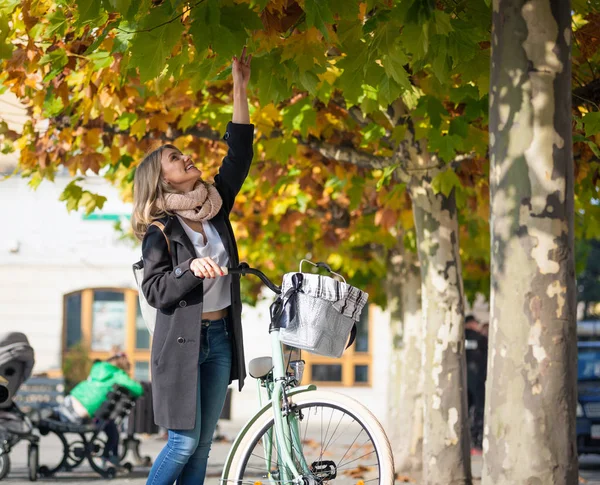 Donna con bicicletta vintage sotto colorati alberi autunnali in città — Foto Stock