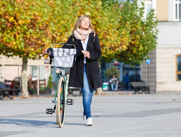Молодая женщина с винтажным велосипедом в осеннем городе — стоковое фото