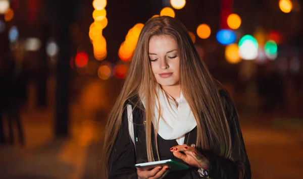 Hermosa mujer usando tableta en la ciudad por la noche —  Fotos de Stock