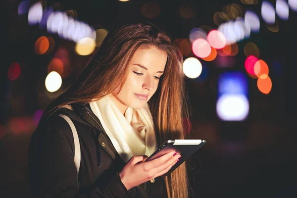 Hermosa mujer usando tableta en la ciudad por la noche —  Fotos de Stock