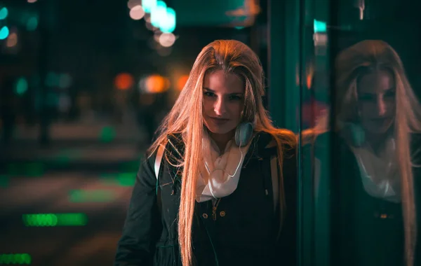 Beautiful woman at night in the city among colorful lights