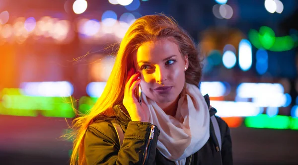 Mujer usando teléfono móvil por la noche en la ciudad entre luces de neón — Foto de Stock