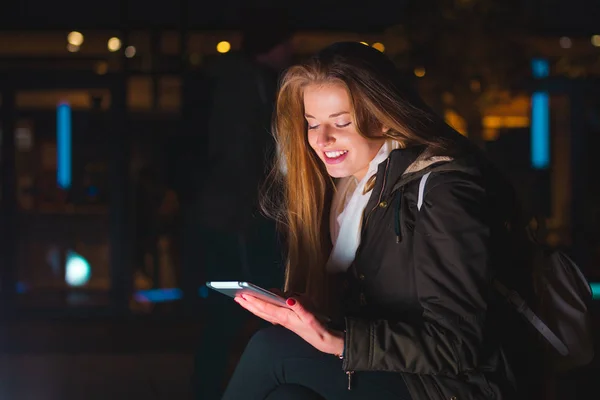 Menina na cidade à noite usando tablet sentado no banco — Fotografia de Stock