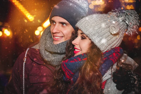 Verschneiter Abend auf dem traditionellen Weihnachtsmarkt, Paar in warmer Winterkleidung — Stockfoto