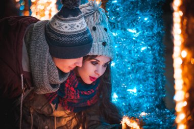 Noel'de genç çift akşam şehirde yürüyüş sırasında dekorasyon ışıklar
