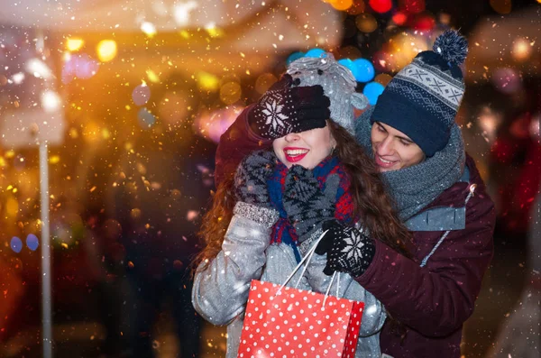 Człowiek, dając prezent-niespodzianka dla swojej dziewczyny, Jarmark bożonarodzeniowy w śnieżysty wieczór — Zdjęcie stockowe