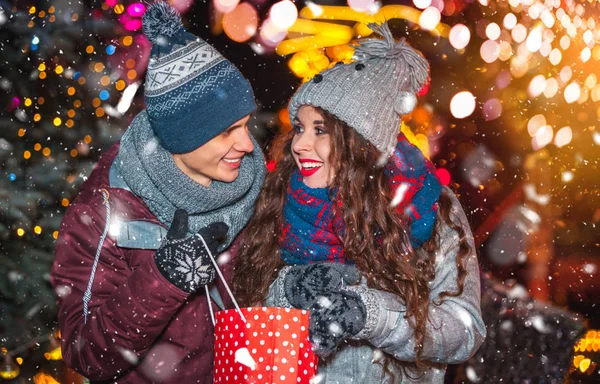 Człowiek, dając prezent-niespodzianka dla swojej dziewczyny, Jarmark bożonarodzeniowy w śnieżysty wieczór — Zdjęcie stockowe