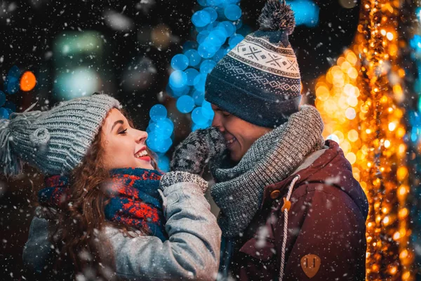 Couple aimant sur fond de lumières de Noël pendant la marche du soir dans la ville avec des chutes de neige — Photo