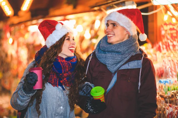 Mutlu çiftimiz Noel Pazar akşam zevk sıcak içecekler sıcak giysiler içinde