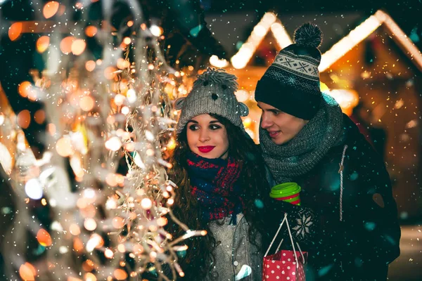 Paar in warmen Kleidern genießen farbenfrohen Weihnachtsmarkt, Bokeh Lichter Hintergrund — Stockfoto