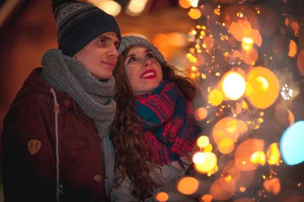 Paar in warmen Kleidern genießen farbenfrohen Weihnachtsmarkt, Bokeh Lichter Hintergrund — Stockfoto