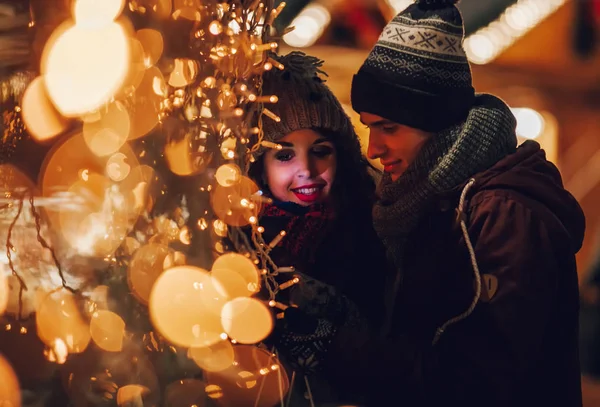 Paar in warmen Kleidern genießen farbenfrohen Weihnachtsmarkt, Bokeh Lichter Hintergrund — Stockfoto