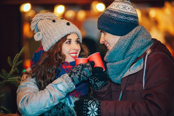 Paar mit Heißgetränken amüsiert sich auf Weihnachtsmarkt — Stockfoto