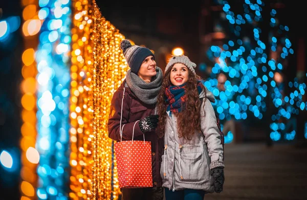 Noel'de hediye çanta ile çift arka plan şehirde akşam yürüyüş, ışıklar