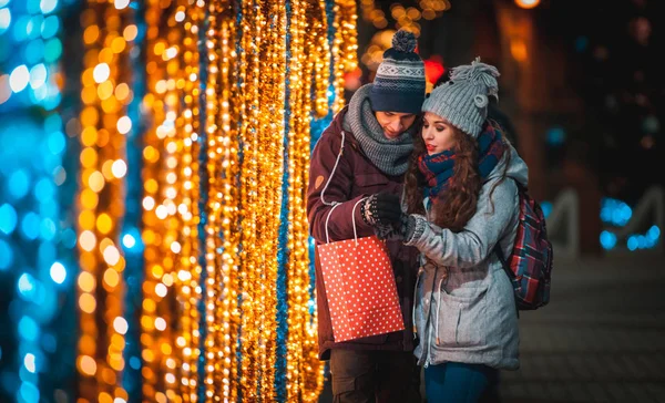 Pár s taštička na vánoční osvětlení pozadí, chůze ve městě na večer — Stock fotografie