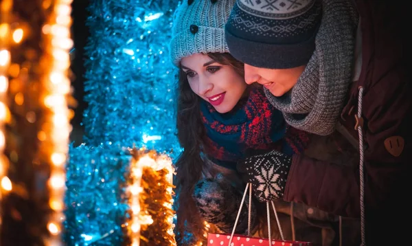 Noel'de genç çift akşam şehirde yürüyüş sırasında dekorasyon ışıklar