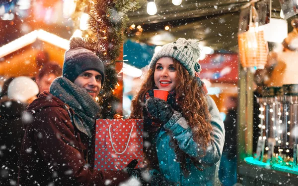 Weihnachtsmarkt-Restaurant am Abend bei Schneefall, Paar mit Heißgetränken in märchenhafter Umgebung — Stockfoto