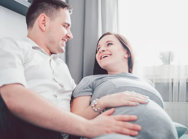 Веселая беременная пара отдыхает дома и наслаждается временем беременности — стоковое фото