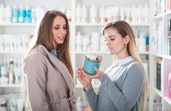 Mujer cliente elegir cosméticos con asistente en la tienda de belleza —  Fotos de Stock