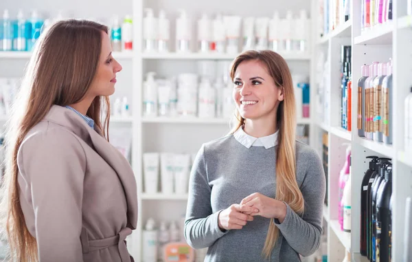 Mujer cliente elegir cosméticos con asistente en la tienda de belleza —  Fotos de Stock