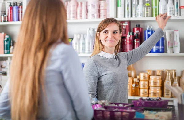 Klient kobieta wybierając kosmetyki z asystentem w piękno przechowywać — Zdjęcie stockowe
