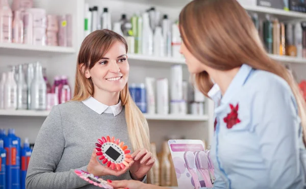 Cliente eligiendo uñas artificiales con asistente en la tienda de belleza —  Fotos de Stock